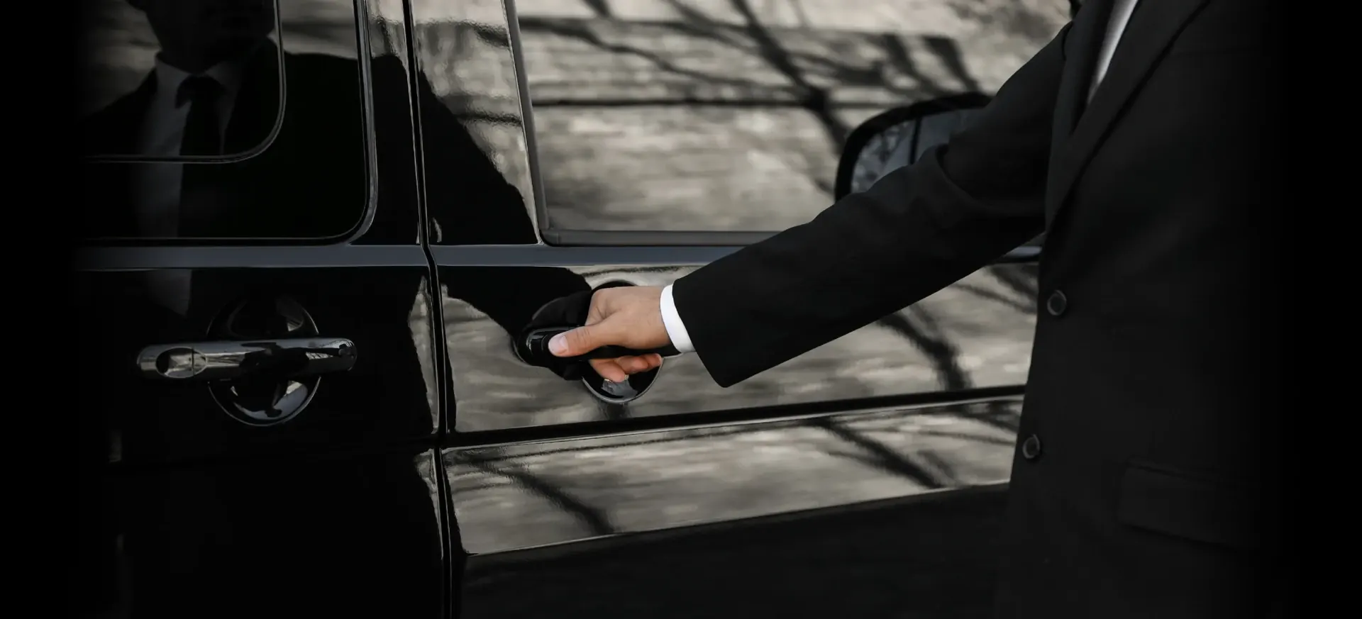 Chauffeur opening the door of a black car